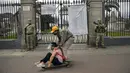 Sepasang kekasih bermain skate saat tentara berjaga di luar Pemakaman Maestro Presbitero, Lima, Peru, Minggu (1/11/2020). Untuk membantu mencegah penyebaran COVID-19, pihak berwenang menutup semua pemakaman secara nasional selama perayaan Day of the Dead. (AP Photo/Rodrigo Abd)