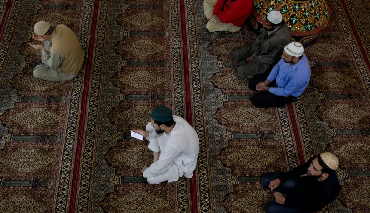 Pria Kashmir membaca Alquran dari ponsel saat bulan ramadan di masjid tertua Masjid Shah-e-Hamdan, di Srinagar, Kashmir yang dikuasai India, 9 Mei 2019. Umat Islam di seluruh dunia sedang menjalankan puasa Ramadan dengan menahan lapar, haus, dan hawa nafsu mulai fajar hingga senja. (AP/Dar Yasin)