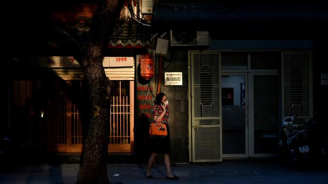 Seorang perempuan berbicara menggunakan smartphone sambil berjalan di trotoar di Hanoi, ibu kota Vietnam pada 11 Agustus 2020. Setelah mencatat nol kasus COVID-19 selama lebih dari tiga bulan, Vietnam melaporkan sejumlah infeksi baru di dalam negeri sejak akhir Juli. (MANAN VATSYAYANA/AFP)