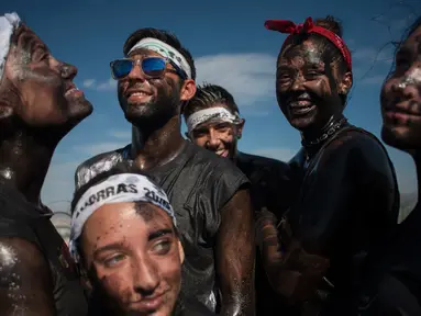 Orang-orang dengan tubuh dilumuri minyak hitam tertawa saat mengikuti festival tradisional Cascamorras di Baza, Spanyol, Rabu (6/9). Festival ini biasa dilakukan tanggal 6 September setiap tahunnya. (JORGE GUERRERO/AFP)