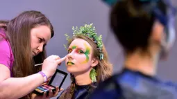 Seorang makeup artist merias model saat mengikuti kompetisi makeup di International "Crystal Angel" Festival of Hairdressing ke-15 di Kiev (22/4). (AFP/Sergei Supinsky)