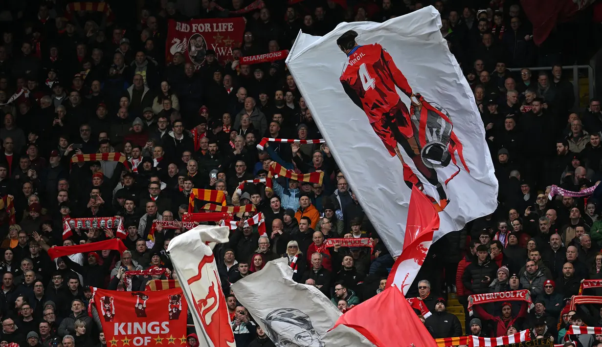 Fans Liverpool mengibarkan bendera bergambarkan Virgil van Dijk pada laga lanjutan Liga Inggris 2022/2023 melawan Manchester United di Anfield, Liverpool, Inggris, 5 Maret 2023. (AFP/Paul Ellis)