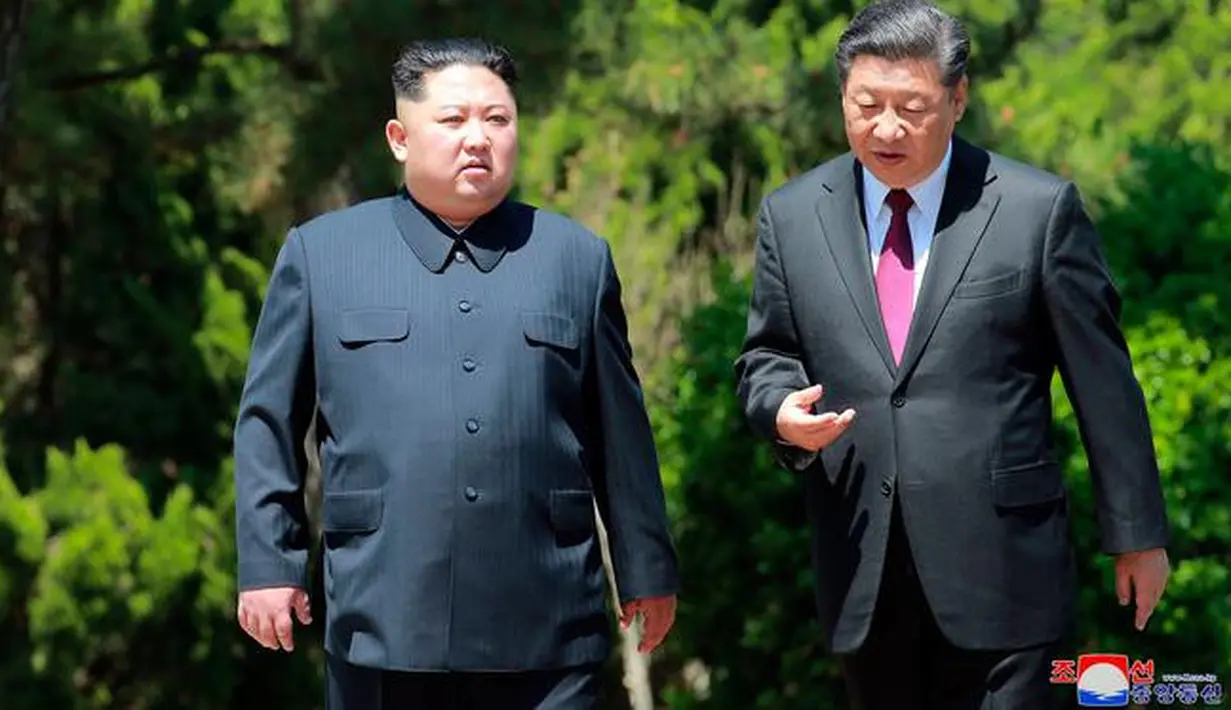 Pemimpin Korea Utara Kim Jong-un dan Presiden China Xi Jinping berbincang sambil berjalan di sela pertemuan di Dalian, Selasa (8/5). Ini adalah kunjungan kedua Kim ke China dalam dua bulan terakhir. (Korean Central News Agency/Korea News Service via AP)
