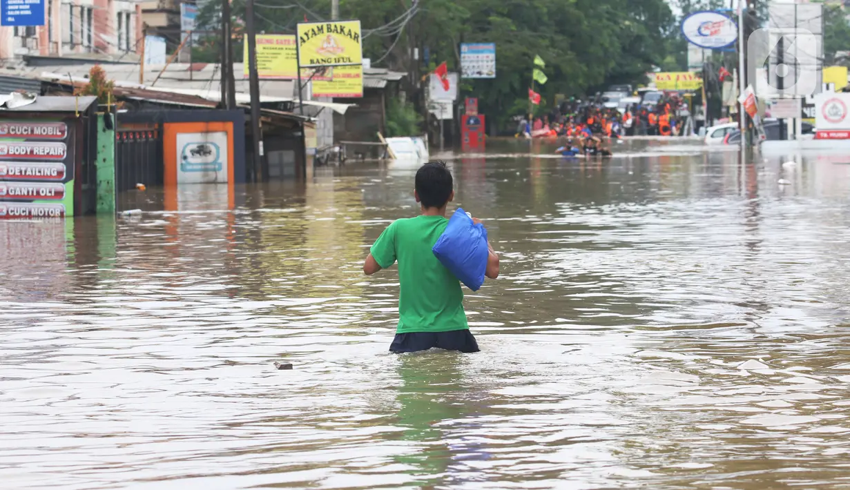 Warga melintasi banjir  yang merendam jalan Raya KH Hasyim Ashari, Ciledug ,Tangerang, Rabu (1/1/2020). Banjir setinggi dada orang dewasa membuat jalur penghubung Tangerang ke Jakarta tersebut terputus tidak dapat dilintasi. (Liputan6.com/Angga Yuniar)