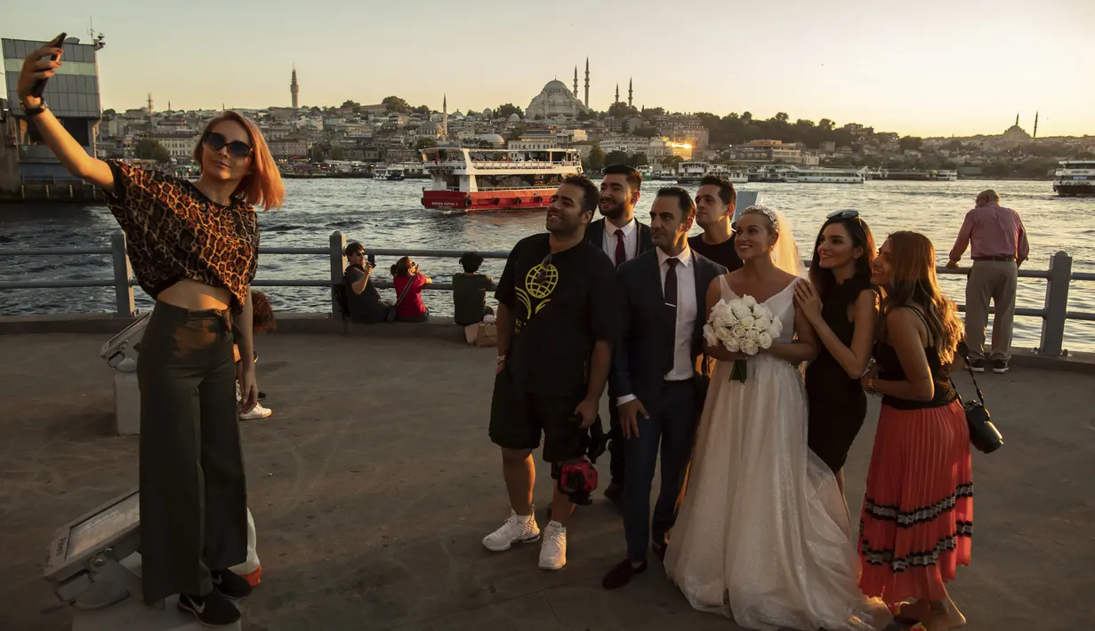 Wisatawan dari Iran berswafoto di Jembatan Galata di atas Tanduk Emas di Istanbul (26/7/2019). Sampai 1980-an Tanduk Emas merupakan tanah tempat pembuangan limbah industri, tetapi sejak setelah dibersihkan merupakan daya tarik wisata yang terkenal di Istanbul. (AP Photo/Emrah Gurel)