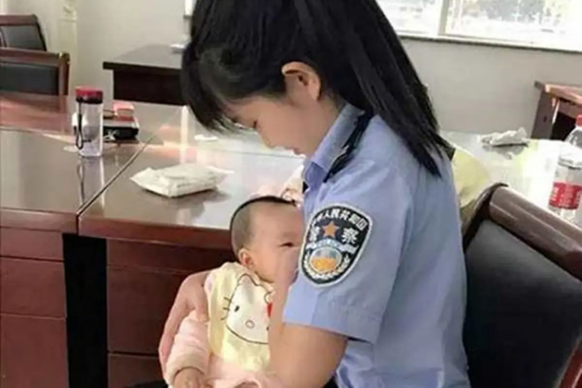 Seorang petugas pengadilan menyusui anak perempuan yang tengah diadili. (China Daily/Asia News Network)