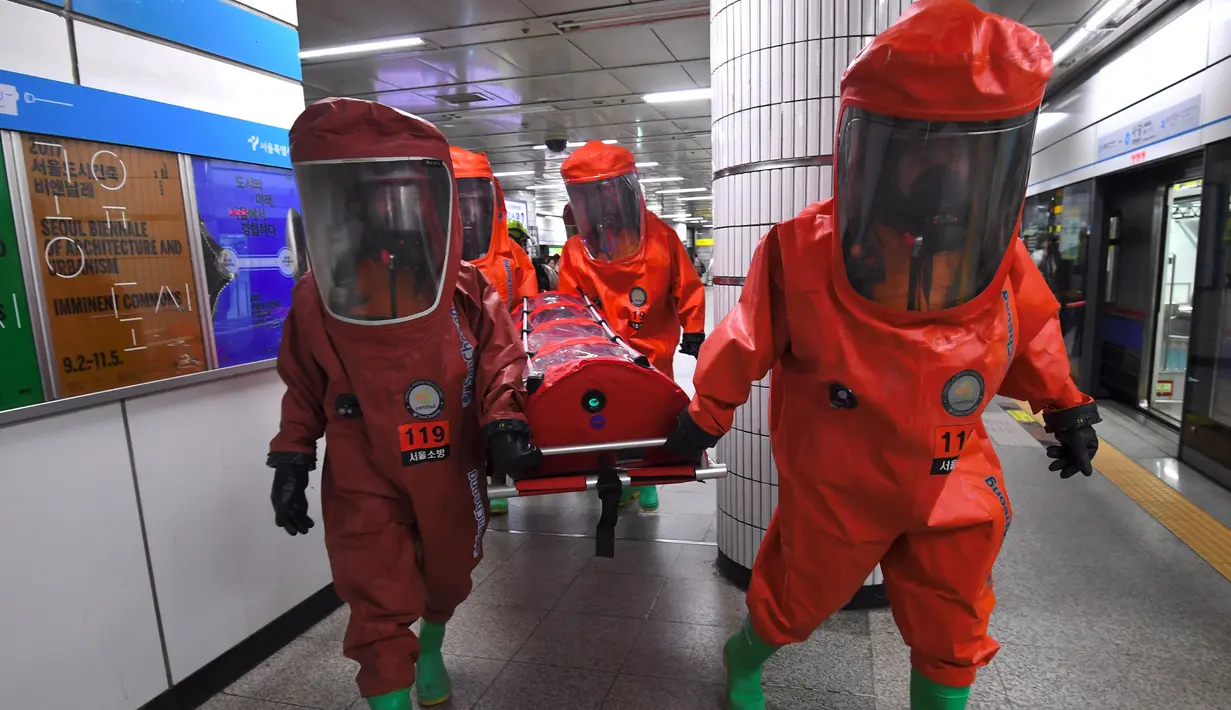 Anggota penyelamat Korea Selatan mengenakan pakaian pelindung kimia ikut serta dalam latihan anti-teror di sebuah stasiun kereta bawah tanah di Seoul (22/8). (AFP Photo/Jung Yeon-Je)