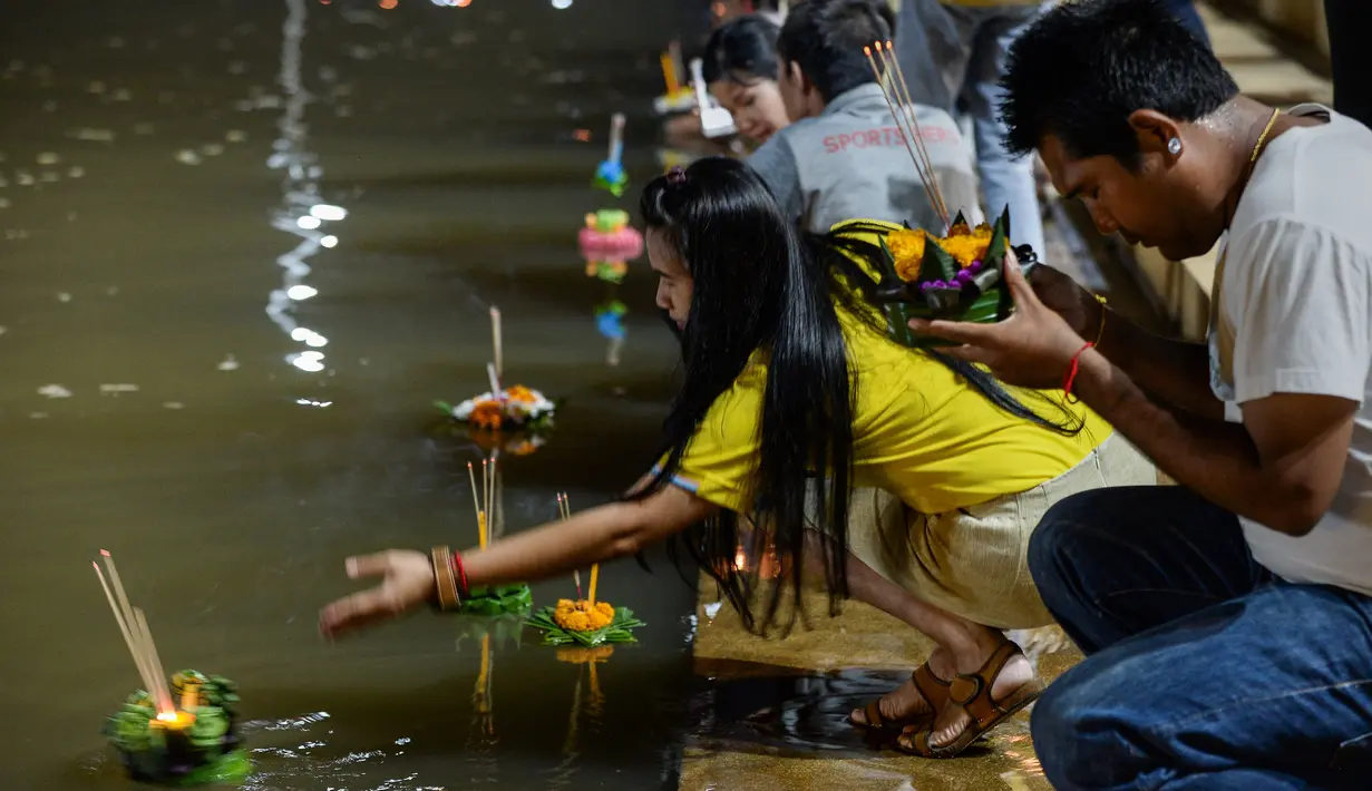 Orang-orang menghanyutkan 'krathong' untuk menandai festival Loy Krathong di sebuah danau di Narathiwat, Thailand,  Senin (11/11/2019). Loi bermakna melarung/mengapung, sedangkan Krathong bermakna wadah yang terbuat dari daun yang bisa mengapung di atas air. (Madaree TOHLALA / AFP)