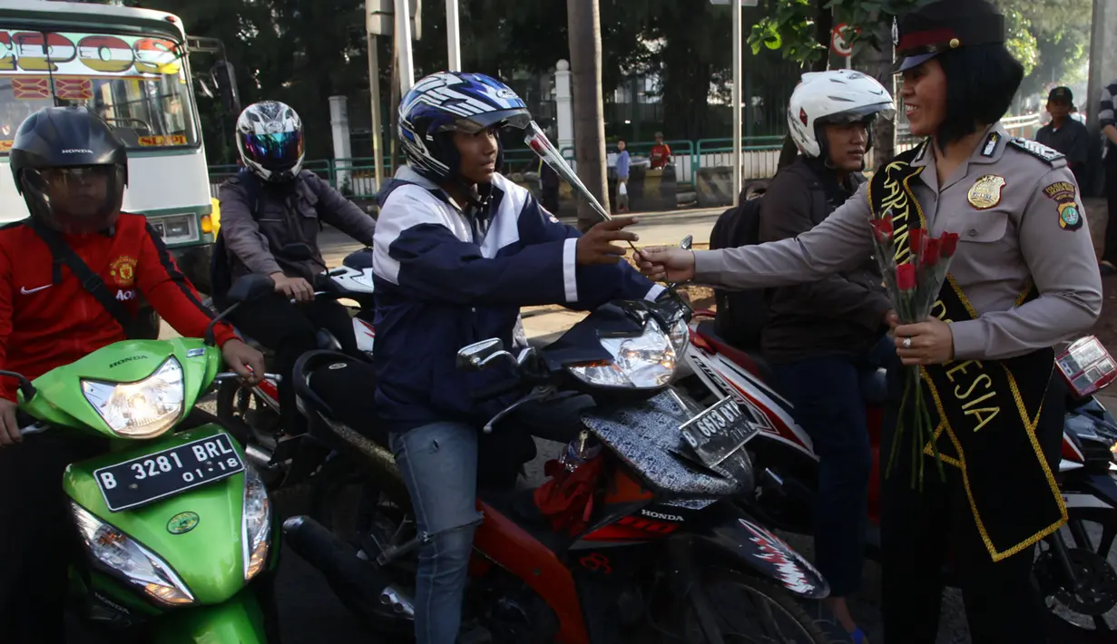 Para pengendara motor di kawasan Slipi mendapat bunga dari seorang Polwan, Jakarta, Selasa (21/4/2015). Pembagian bunga ini dalam rangka memperingati hari Kartini.(Liputan6.com/Johan Tallo)