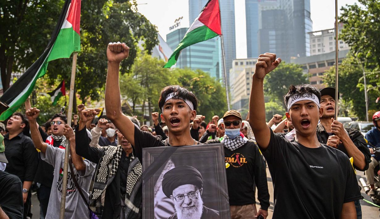 Oleh karena itu, peringatan ini disebut juga sebagai Hari Yerusalem. Taampak dalam foto, seorang pria memegang plakat bergambar pemimpin tertinggi Iran, Ayatollah Ali Khamenei yang gugur dalam serangan Amerika Serikat dan Israel pada akhir Februari lalu, selama berunjuk rasa memperingati Hari Al-Quds, di Surabaya, Jawa Timur, Jumat (13/3/2026). (Juni KRISWANTO/AFP)