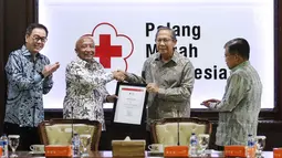 Plh Ketum PMI Ginandjar Kartasasmita memberikan penghargaan kepada Astra International yang diwakili Chief of Corcomm, Social Responsibility & Security Astra International Pongki Pamungkas di Kantor PMI, Jakarta, Jumat (8/2). (Liputan6.com/Fery Pradolo)