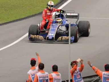 Pebalap Ferrari, Sebastian Vettel terpaksa menumpang mobil rekan senegaranya, Pascal Wehrlein setelah terlibat kecelakaan pada balapan Formula One Malaysia Grand Prix, Sepang, (01/10/2017). Vettel akhirnya finis pada posisi keempat. (AFP/Roslan Rahman)