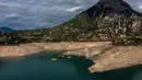 Foto ini menunjukkan sisa-sisa rumah yang muncul kembali ketika permukaan danau buatan Mornos menurun akibat kekeringan, di desa Kallio, sekitar 240 km barat laut Athena, Yunani pada 3 November 2025. Kemunculan kembali desa tersebut disebabkan oleh kekeringan parah dan tingkat air danau yang menurun drastis ke level terendah dalam beberapa dekade, akibat musim dingin dengan sedikit salju, gelombang panas, dan curah hujan yang rendah di Yunani. (Angelos TZORTZINIS/AFP)