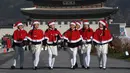 Anak-anak Korea Selatan mengenakan pakaian Santa Claus berjalan di depan Istana Gyeongbokgung, Seoul, Jumat (30/11). Anak-anak tersebut bersiap meluncurkan kampanye penggalangan dana akhir tahun dari The Salvation Army. (Jung Yeon-je/AFP)