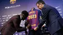 Bek asal Prancis, Samuel Umtiti menandatangani jerseynya disaksikan Presiden Barcelona FC, Josep Maria  pada pengumuman perpanjangan kontraknya di Camp Nou, Senin (4/6). Umtiti memperpanjang kontraknya bersama Barcelona hingga 2022. (LLUIS GENE/AFP)