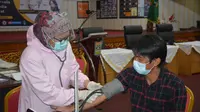 Ketua IJTI Sumbar, John Nedy Kambang melakukan cek kesehatan sebelum vaksinasi Covid-19. (Liputan6.com/ Humas Pemprov Sumbar).