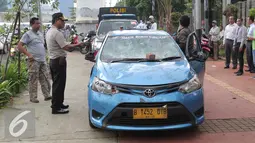 Petugas mengamankan mobil taksi yang hancur akibat dirusak oleh ojek online di Jakarta, Selasa (22/3). Akibat aksi saling serang antara taksi dan ojek online berimbas pada kerusuhan yang terjadi di beberapa titik di Jakarta. (Liputan6.com/Angga Yuniar)