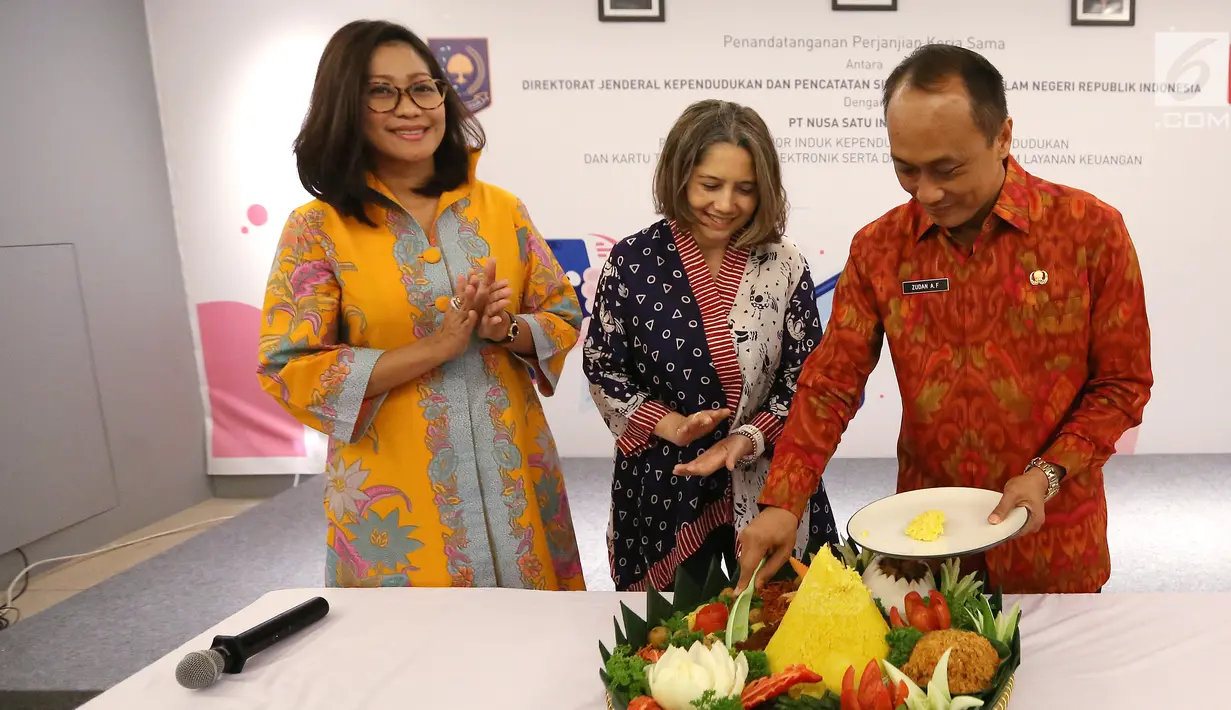 Chief Marketing Officer DOKU, Himelda Renuat, Chief Operating Officer, Nabilah Alsagoff dan Dirjen Dukcapil Zudan Arif Fakrulloh potong tumpeng usai kerja sama pemanfaatan data kependudukan di Jakarta, Jumat (11/1). (Liputan6.com/Fery Pradolo)