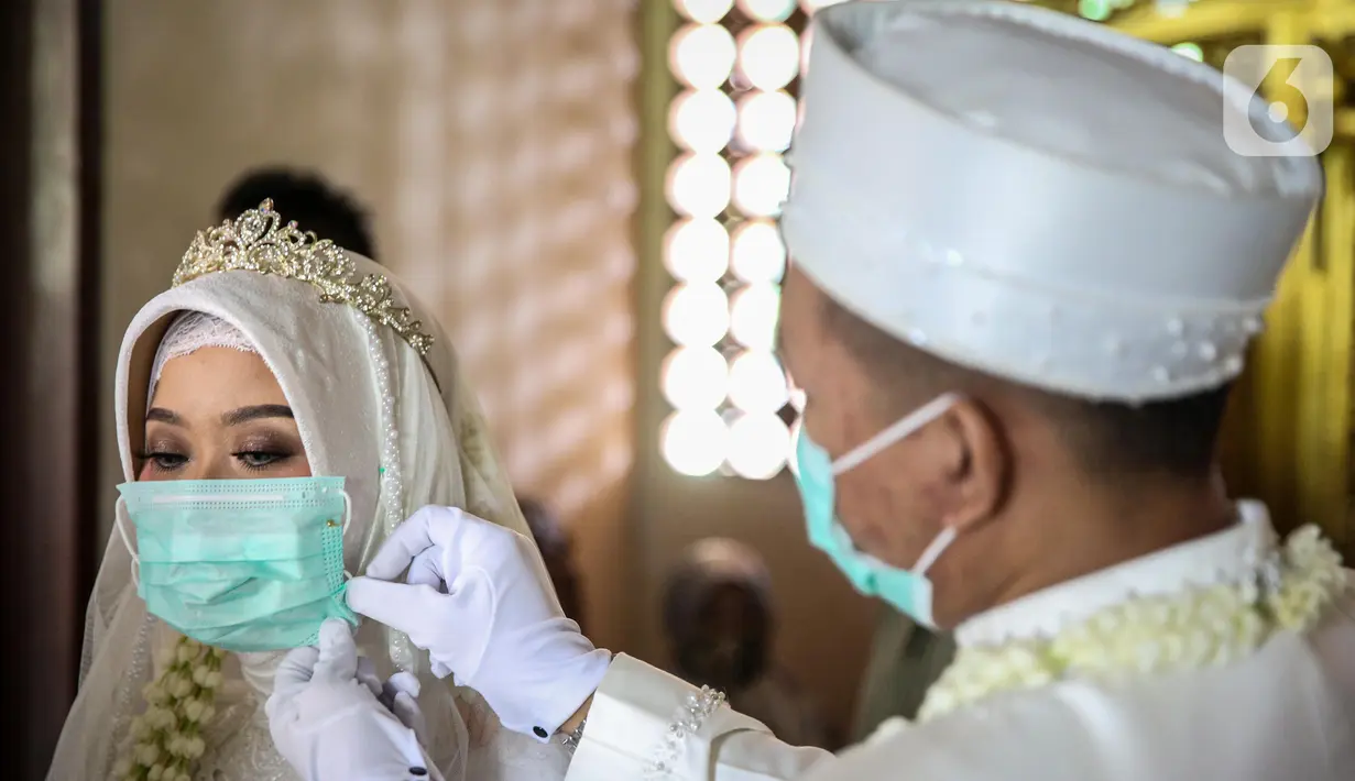 Pasangan pengantin menggunakan masker sebelum melaksanakan prosesi akad nikah di KUA Jagakarsa, Jakarta, Sabtu (6/6/2020). Pada masa penerapan PSBB transisi, pihak KUA tersebut menikahkan sebanyak delapan hingga 10 pasangan pengantin per hari. (Liputan6.com/Faizal Fanani)