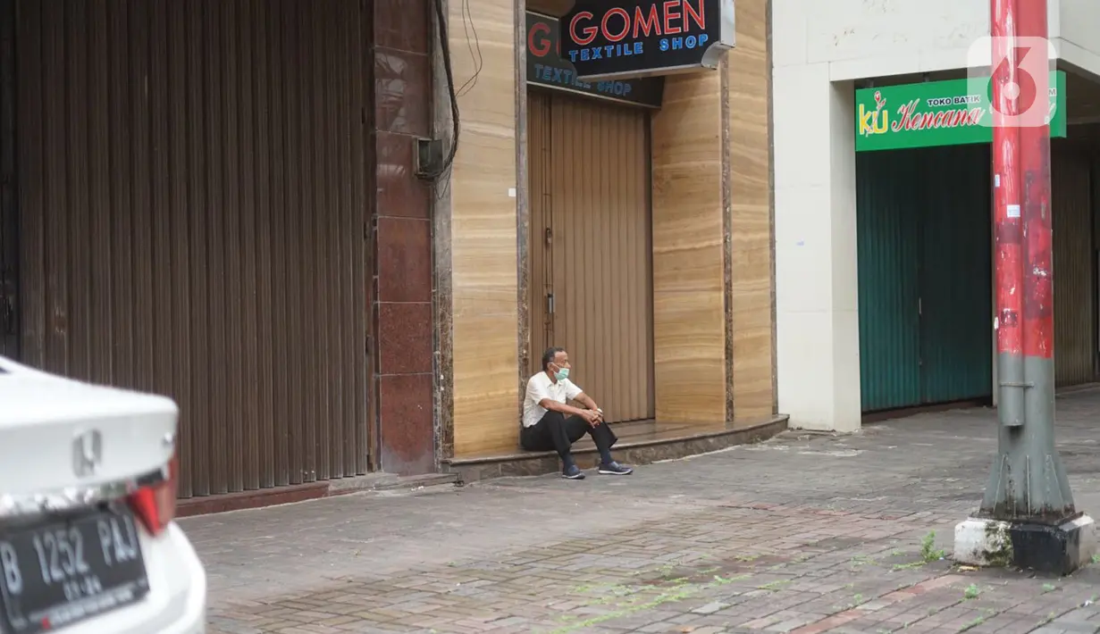 Seorang pria duduk di depan toko di Pasar Baru, Jakarta Pusat, Senin (4/5/2020). Adanya program PSBB menyebabkan hampir seluruh pertokoan di salah satu pusat tekstil Ibukota tersebut berhenti beroperasi dan lebih sepi dibanding hari biasa. (Liputan6.com/Immanuel Antonius)