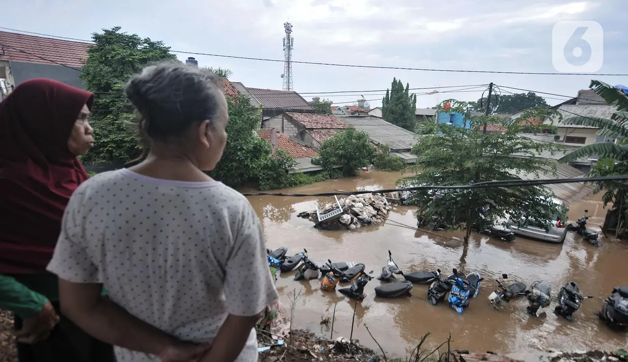 Warga melihat kondisi banjir yang merendam permukiman Cipinang Melayu, Jakarta, Rabu (1/1/2020). Ratusan rumah warga di Kelurahan Cipinang Melayu terendam banjir hingga ketinggian leher orang dewasa sejak dini hari tadi dan telah menewaskan dua warga. (merdeka.com/Iqbal S Nugroho)