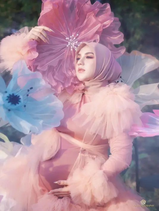 Maternity shoot yang dilakukan Irish Bella juga luar biasa. Ia tampil dreamy dengan outfit hijab super cantik bernuansa merah muda dengan properti bunga-bunga berukuran besar yang serasi. [Foto: Instagram/fdphotography90]
