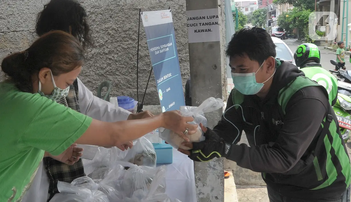 Pengemudi ojek online menerima nasi bungkus gratis di Kompleks Sinar Pamulang Permai, Pamulang Barat, Tangerang Selatan, Senin (13/4/2020). Setiap siang dan malam disediakan sekitar 100 bungkus nasi gratis oleh sekelompok warga dan pemuda Kompleks Sinar Pamulang Permai. (merdeka.com/Arie Basuki)