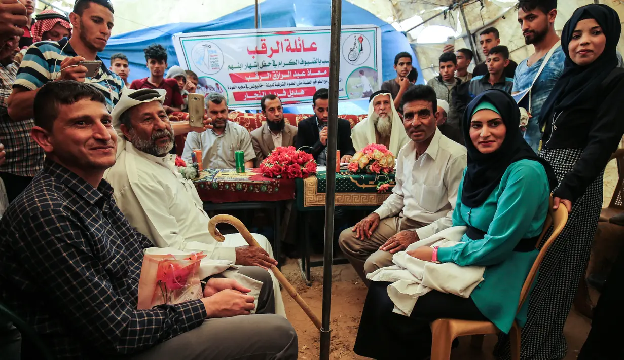 Petugas medis Muadh Al-Raqab (kiri) didampingi ayahnya bersiap melangsungkan pernikahannya dengan Hadeel Al-Najjar di dalam tenda jalur Gaza selatan, Palestina (2/5). (AFP Photo/Said Khatib)