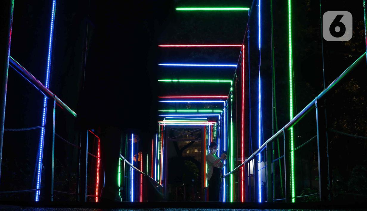 Warga saat memotret Jakarta Lights Festival di Taman Sumenep, Jakarta, Jumat (23/12/2022). Pemprov DKI Jakarta menggelar acara Jakarta Lights Festival sebagai rangkaian perayaan Natal dan Tahun Baru (Nataru) 2023. (Liputan6.com/Herman Zakharia)