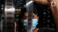 Adul (29) mengecek kualitas film seluloid 35mm untuk pertunjukan layar tancap di gudang rumahnya di Jakarta, Rabu (28/4/2021). (Liputan6.com/Johan Tallo)