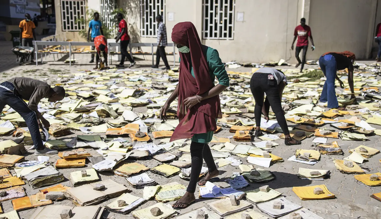 Mahasiswa pengarsipan dan dokumentasi menyaring dokumen yang terbakar di Universitas Cheikh Anta Diop di Dakar pada 09 Juni 2023 dalam upaya untuk menyelamatkannya. (JOHN WESSELS / AFP)