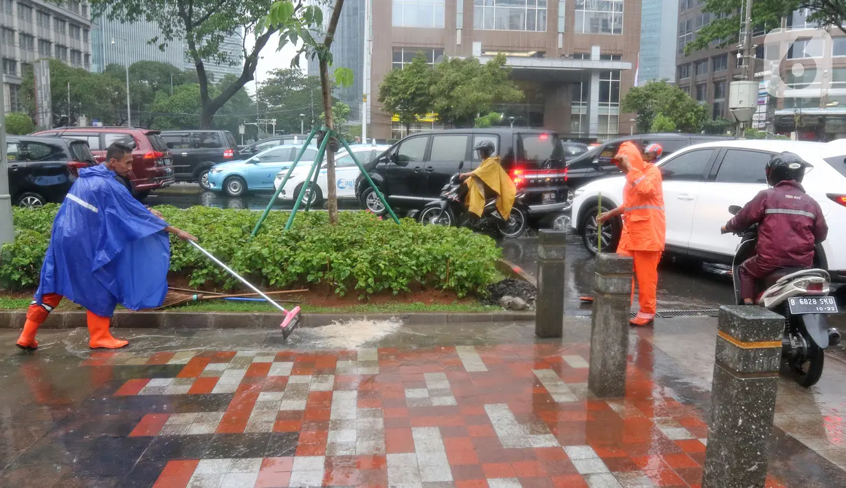 Petugas Penanganan Prasarana dan Sarana Umum (PPSU) membersihkan saluran air di kawasan Gelora Bung Karno, Jakarta, Selasa (17/12/2019). Petugas PPSU membersikan saluran air saat terjadi genangan usai hujan deras mengguyur Jakarta. (Liputan6.com/Herman Zakharia)