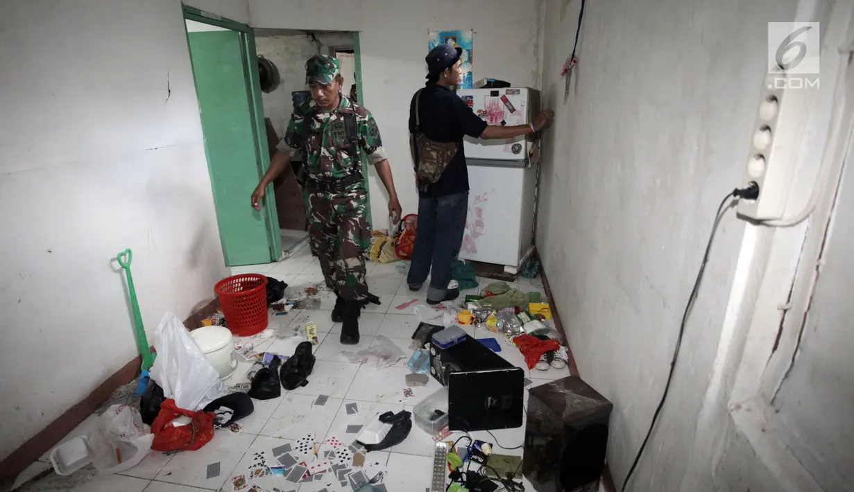 Petugas menyisir sebuah rumah lokasi penggerebekan peredaran narkoba di Kampung Ambon, Jakarta, Rabu (24/1). Penggerebekan dilakukan untuk mengamankan penyalahgunaan narkotika yang kerap dilakukan di Kampung Ambon. (Liputan6.com/Arya Manggala)