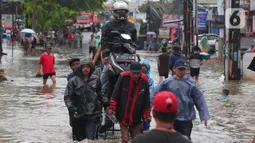 Pengendara bersama sepeda motornya berada di atas gerobak yang didorong pengojek gerobak saat melintasi banjir yang merendam jalan KH Hasyim Ashari, Kota Tangerang, Banten, Sabtu (16/7/2022). Warga sekitar membantu para pengendara yang melintas agar tidak terkena banjir dengan menawarkan jasa gerobak. (Liputan6.com/Angga Yuniar)