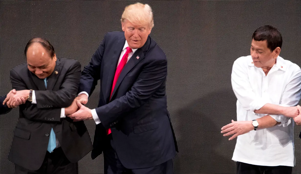 Presiden AS, Donald Trump canggung mengikuti gaya salaman para pemimpin lainnya saat bersalaman khas ASEAN di penghujung upacara pembukaan KTT ASEAN di Manila, Senin (13/11). Trump kesulitan menempatkan tangannya di posisi yang pas. (AP/Andrew Harnik)
