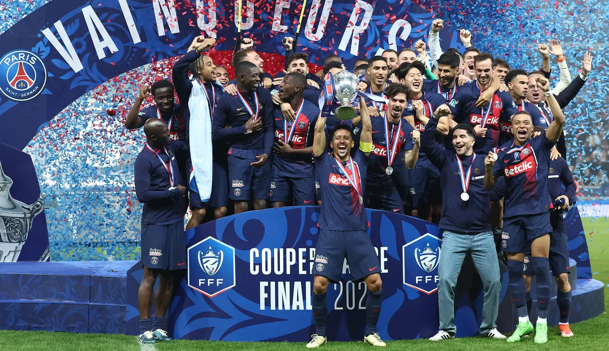 Bek Paris Saint-Germain #05 Marquinhos (tengah) mengangkat trofi Coupe de France 2023/2024 saat berselebrasi dengan timnya setelah menang atas Olympique Lyon pada laga final di Stadion Pierre-Mauroy, Minggu (26/5/2024) dini hari WIB. (FRANCK FIFE / AFP)