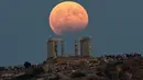 Gerhana bulan parsial terlihat di atas kuil Poseidon di Cape Sounion, Yunani, Senin (7/8). Gerhana bulan parsial terjadi ketika bumi bergerak di antara bulan dan matahari, tapi tidak persis dalam satu garis. (AP Photo/Petros Giannakouris)