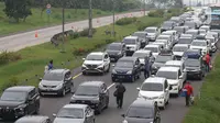 Pedagang menawarkan daganganya ke para pemudik di Jalan tol Cikopo - Palimanan KM 73, Purwakarta, Jawa Barat, Sabtu (30/4/2022). Padatnya arus lalu lintas ruas tol trans jawa, membuat pedagang asongan turun ke jalan. (Liputan6.com/Herman Zakharia)