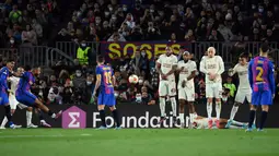 Penyerang Barcelona, Memphis Depay (kiri) melakukan tendangan bebas ke arah gawang Galatasaray pada pertandingan leg pertama babak 16 besar Liga Europa di stadion Camp Nou di Barcelona (11/3/2022). Barcelona bermain imbang atas Galatasaray 0-0. (AFP/Lluis Gene)