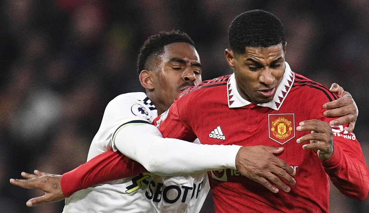 Bek Leeds United Junior Firpo (kiri) berebut bola dengan striker Manchester United (MU) Marcus Rashford pada laga tunda pekan ke-8 Liga Inggris 2022/2023 di Old Trafford, Manchester, Kamis (9/2/2023) dini hari WIB. MU bangkit dengan mencetak dua gol masing-masing lewat sundulan Marcus Rashford (62') dan Jadon Sancho (70'). (Oli SCARFF / AFP)