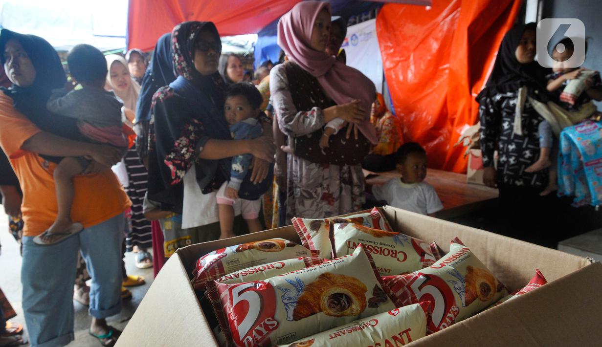 Warga antre mendapatkan pampers dan biskuit bagi anak-anak di Posko pengungsian Mangunkerta, Cianjur, Jumat (23/12/2022). Lebih dari sebulan sejak musibah gempa bumi 5,2 SR sejumlah warga masih tinggal di pengungsian dengan bantuan kebutuhan hidup dari para donatur. (merdeka.com/Arie Basuki)