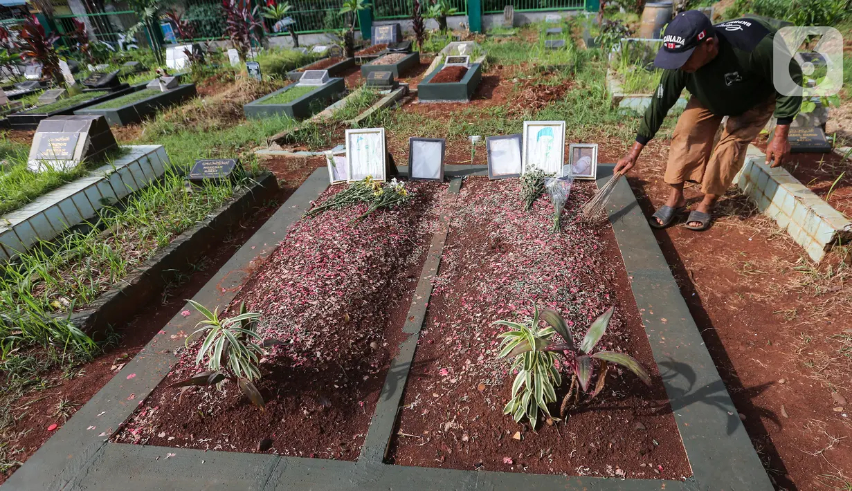 Sardi, pengurus makam membersihkan makam Vanessa Angel dan Bibi Ardiansyah di TPU Taman Makam Islam Malaka Blok D, Pesanggrahan, Jakarta, Senin (7/02/2022). H. Faisal menginginkan makam Vanessa Angel tetap bersebelahan dengan putranya, Bibi Andriansyah. (Liputan6.com/Fery Pradolo)