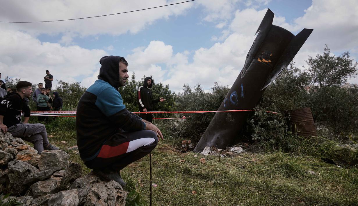 Diketahui, serangan ini merupakan bagian dari gelombang serangan balasan Iran setelah operasi militer gabungan Amerika Serikat dan Israel terhadap Teheran pada 28 Februari 2026 yang menewaskan Pemimpin Tertinggi Iran, Ayatollah Ali Khamenei. Tampak dalam foto, warga Palestina berkumpul di sekitar puing-puing rudal Iran yang jatuh di desa Kifl Haris, Tepi Barat, Selasa, 24 Maret 2026. (AP Photo/Majdi Mohammed)