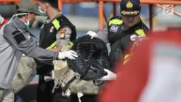 Polisi membawa tas korban jatuhnya pesawat Lion Air JT 610 di Tanjung Priok, Jakarta Utara, Senin (29/10). Petugas menemukan tas, sandal, pakaian, koper dan sebagainya. (Merdeka.com/Iqbal Nugroho)