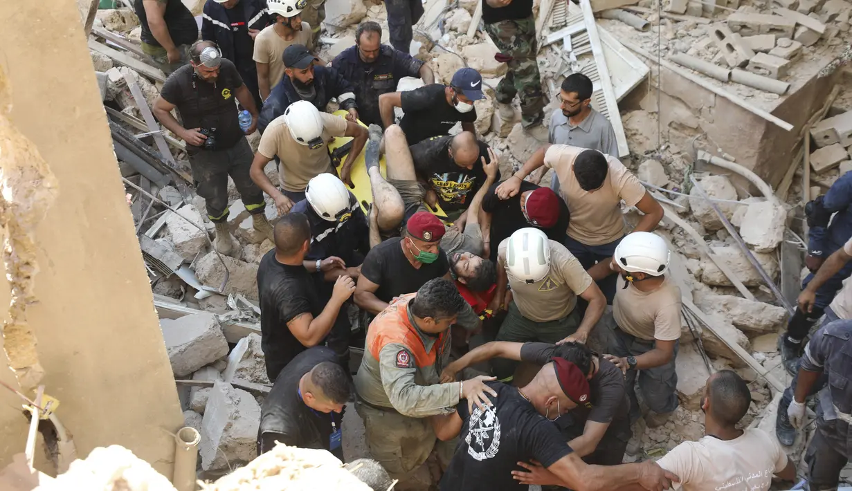 Tim penyelamat membawa korban selamat yang dikeluarkan dari puing-puing setelah ledakan besar di Beirut, Lebanon, Rabu (5/8/2020). Ledakan yang mengakibatkan puluhan orang tewas dan ribuan lainnya terluka tersebut meratakan pelabuhan dan merusak bangunan di seluruh Beirut. (AP Photo/Hassan Ammar)