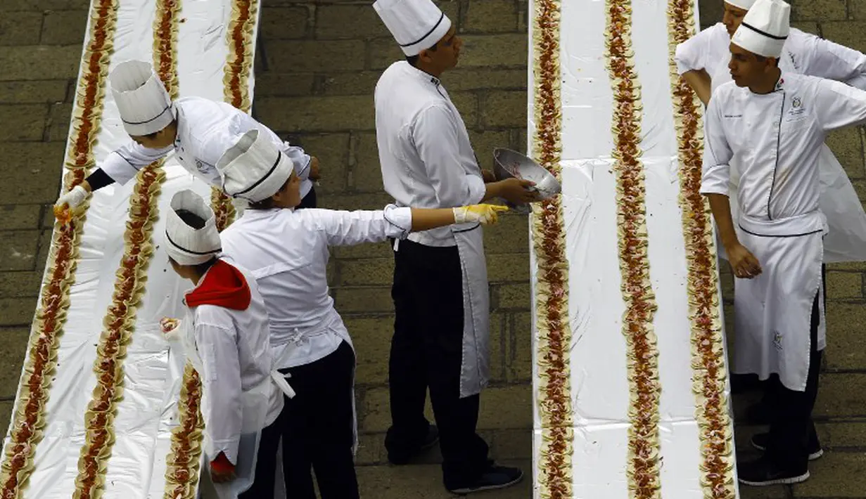 Para koki menambahkan bumbu untuk 80.000 Tacos, di Guadalajara, Meksiko, 15 Februari 2015. Susunan Taco sepanjang 2,5 km tersebut memecahkan rekor dunia versi Guinness.(AFP Photo/Hector Guerrero)