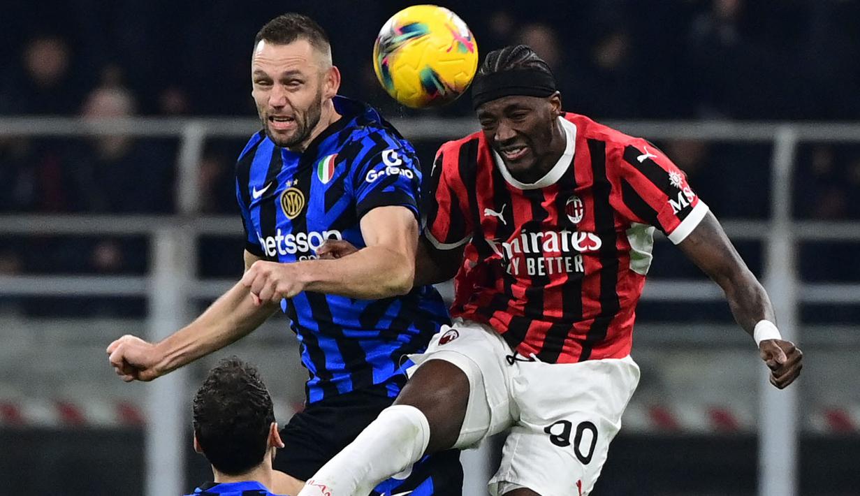Pemain Inter Milan, Stefan de Vrij (kiri) berduel udara dengan pemain AC Milan, Tammy Abraham dalam laga lanjutan Liga Italia 2024/2025 di San Siro, Milan, Italia, Senin (03/02/2025) WIB. (AFP/Piero Cruciatti)