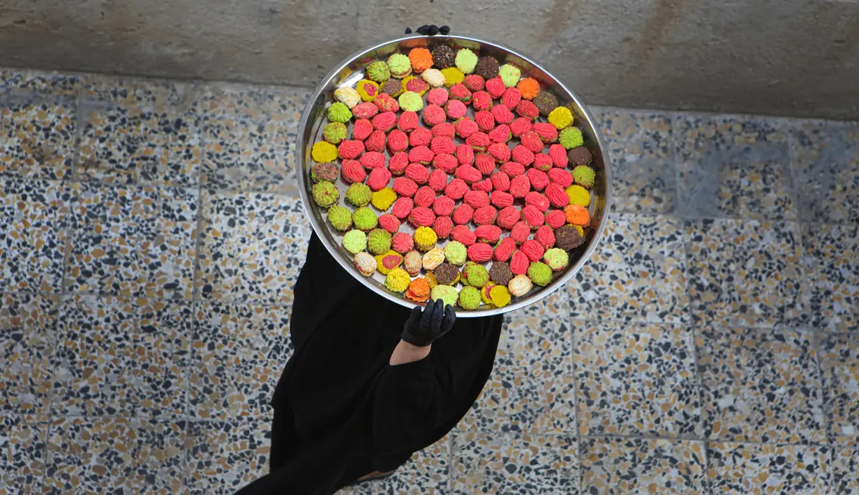 Seorang perempuan membawa kue untuk perayaan Idul Fitri yang akan datang di Basra, Irak, Jumat (22/5/2020). Idul Fitri menandai berakhirnya bulan suci Ramadan. (AP Photo/Nabil al-Jurani)
