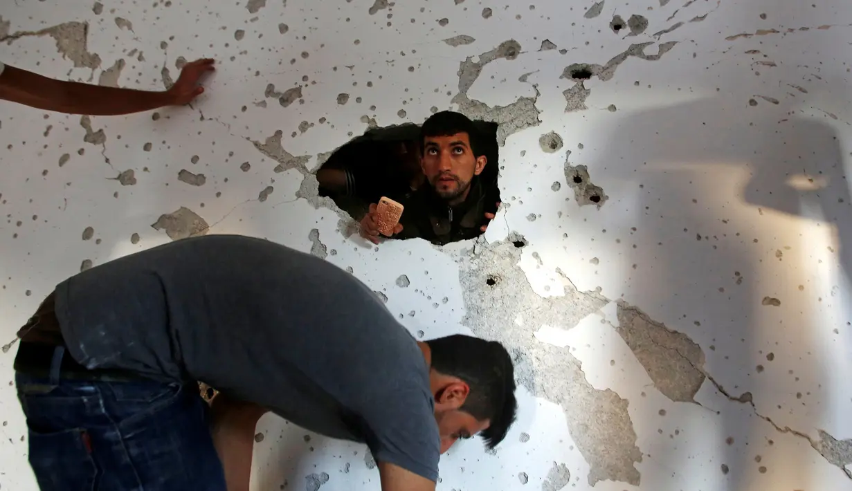 Warga meliha sisa-sisa rumah pejuang Hamas Mohammad Al-Fakih yang rusak di desa Tepi Barat Surif, dekat Hebron, (27/7). (REUTERS/Mussa Qawasma)