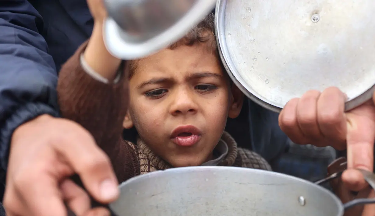 Puluhan ribu anak-anak menjadi korban perang yang sedang berlangsung antara Israel dan Hamas di wilayah Gaza. Tampak dalam foto, seorang anak laki-laki Palestina berusaha mendapatkan makanan dari lokasi distribusi di Kota Gaza pada 19 November 2024. (Omar AL-QATTAA/AFP)